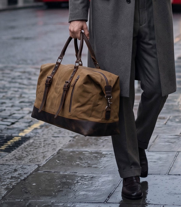 man carrying a waxed canvas and leather holdall in the rain, London